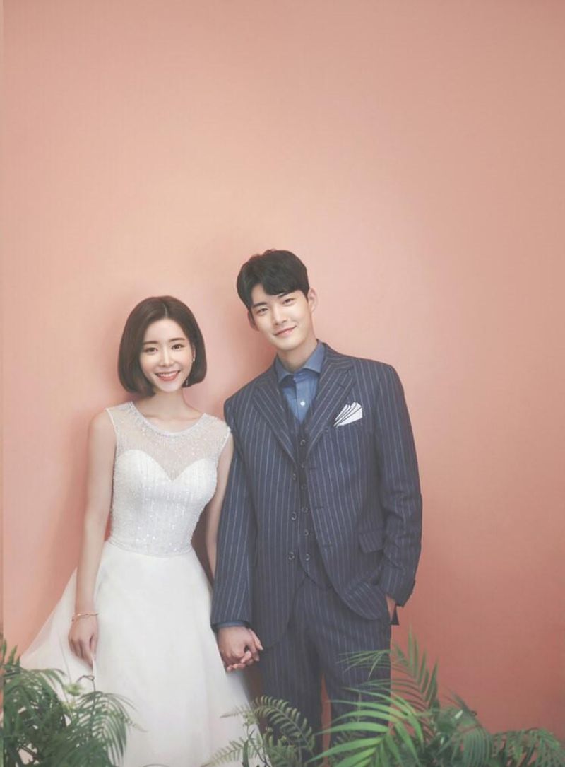 chú rể và cô dâu đứng trước phông nền màu hồng