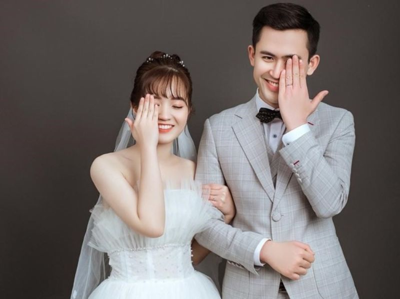 co dâu và chú rể dùng 1 tay che mặt rồi cười thật tươi