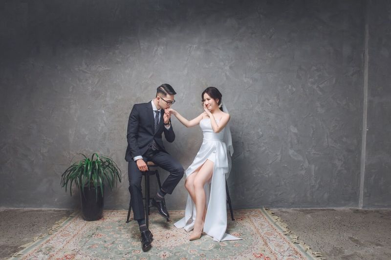 chú rể hôn lên tay cô dâu trong căn phòng xám xịt