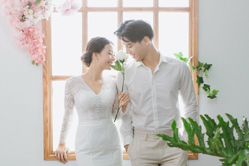 chú rể và cô dâu ngồi trên bệ cửa sổ gổ trong studio