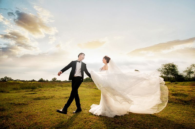 chú rể nắm tat cô dâu bước đi trên bãi cỏ xanh