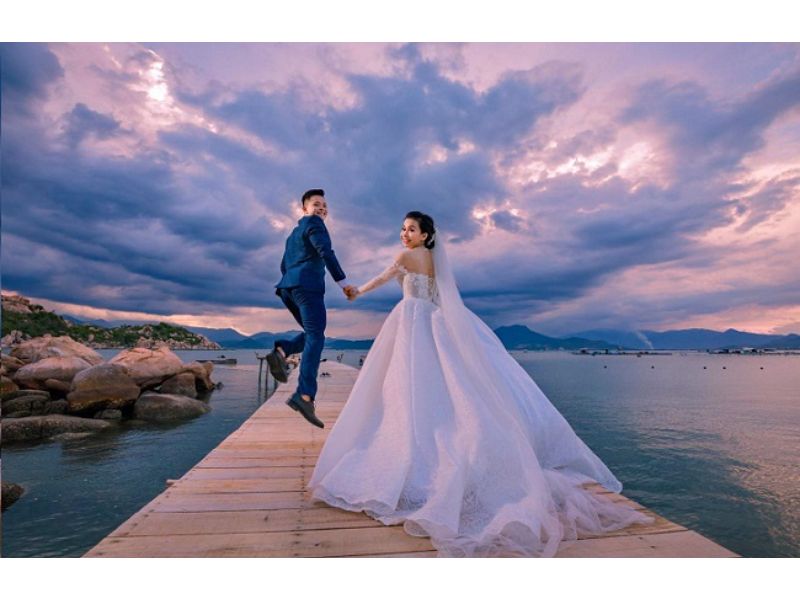 chú rể chạy cùng cô dâu giẵ bầu trời đầy mây