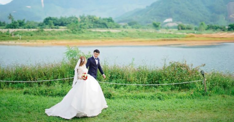 cô dâu chú rể bước đi cùng nhau trên bãi cỏ xanh mướt