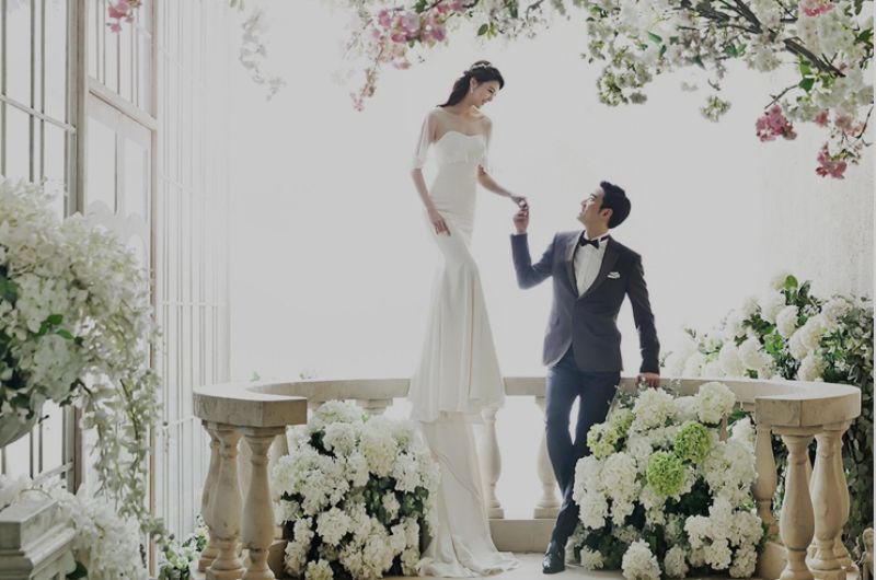 cô dâu đứng trên bậc hoa nắm tay chú rể