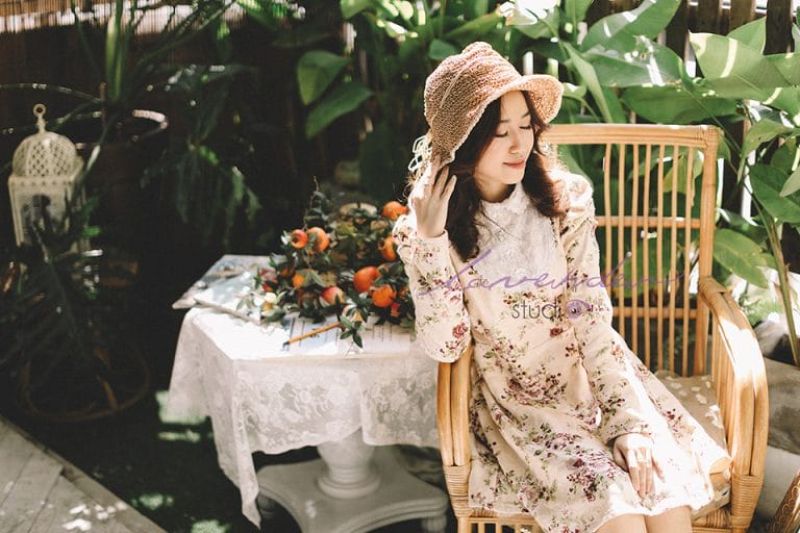 cô gái mặc trang phục giản dị lấy tay kéo nón